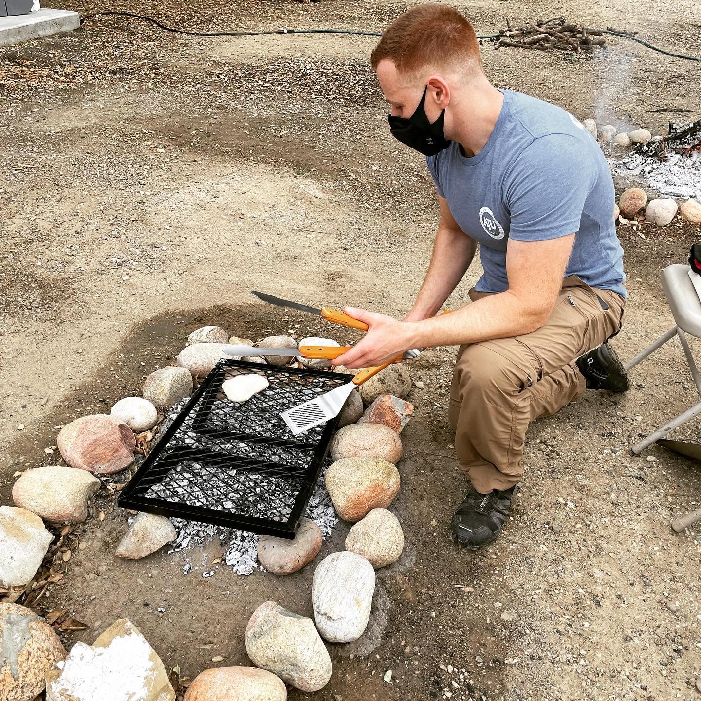 Aryeh Goldman cooking over a campfire at an outdoor education program.