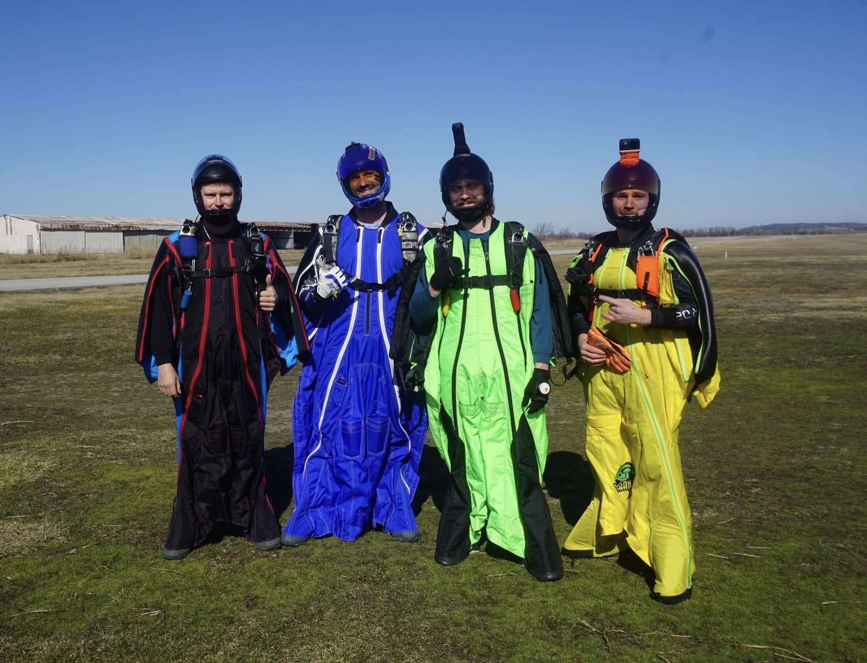 Aryeh Goldman with three other wingsuit flyers on an airfield.